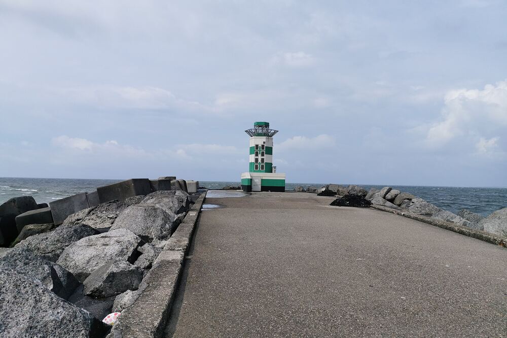 De pier van IJmuiden met het groene havenlicht aan het Noordzeekanaal